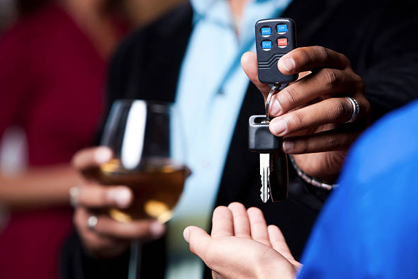 person with wine glass gives keys to sober driver